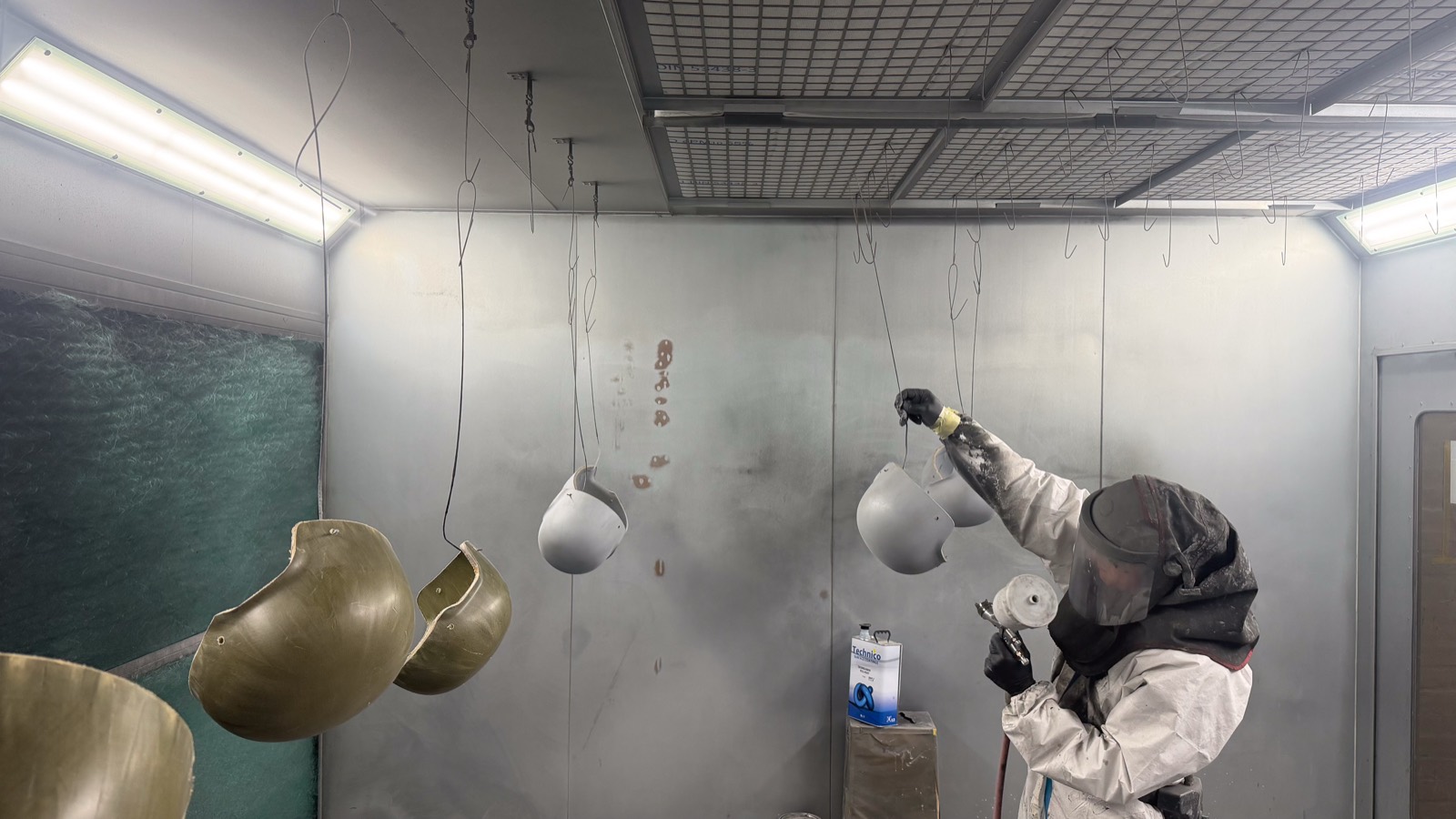 Helmet shells hanging in the spray booth during finishing
